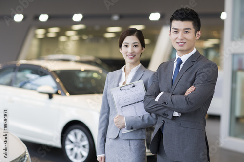 Wallpaper Mural Confident salespeople standing with new cars in showroom Torontodigital.ca