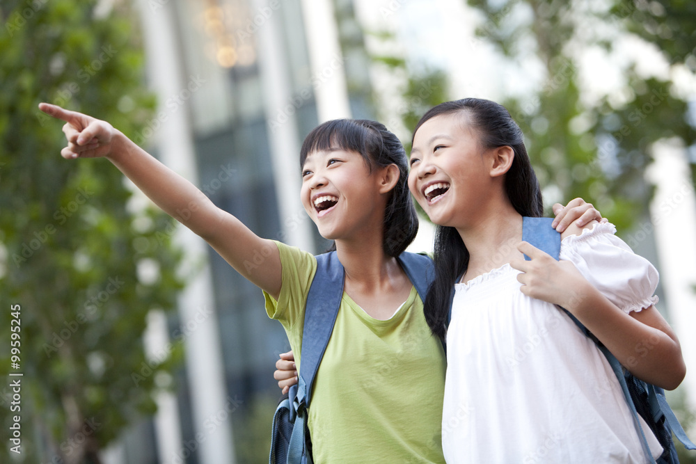 Happy schoolgirls pointing to the front