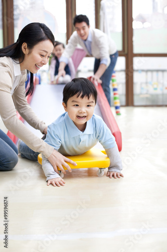 Happy boy going down a slide in kindergarten