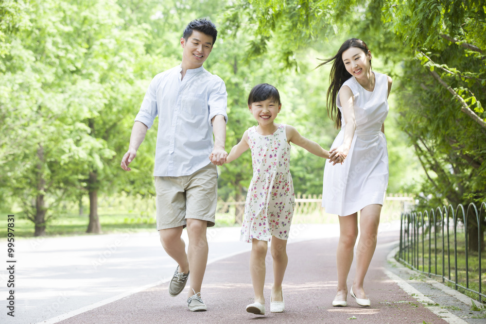 Happy young family walking together in park Happy young family walking together in park