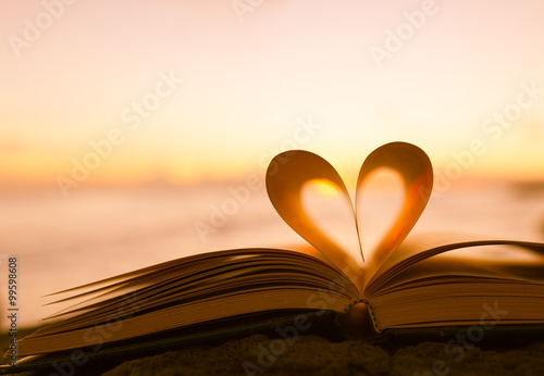 Heart from a book page against a beautiful sunset.
