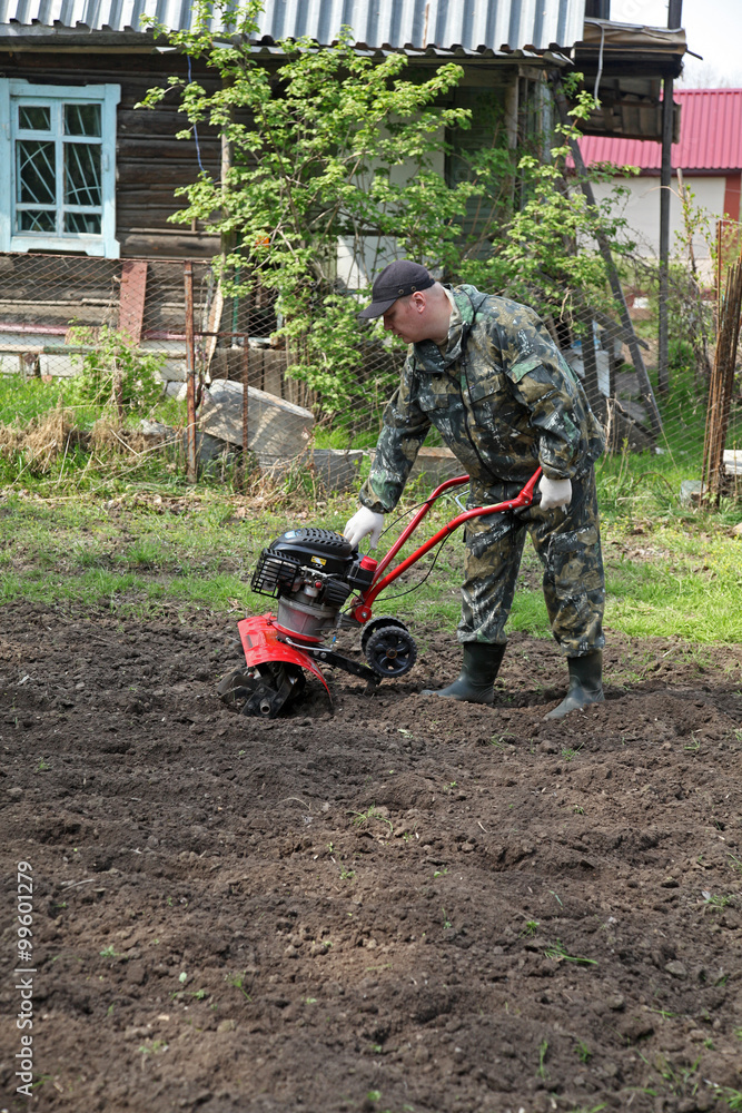 Obraz premium Man working in the garden preparing ground cultivator