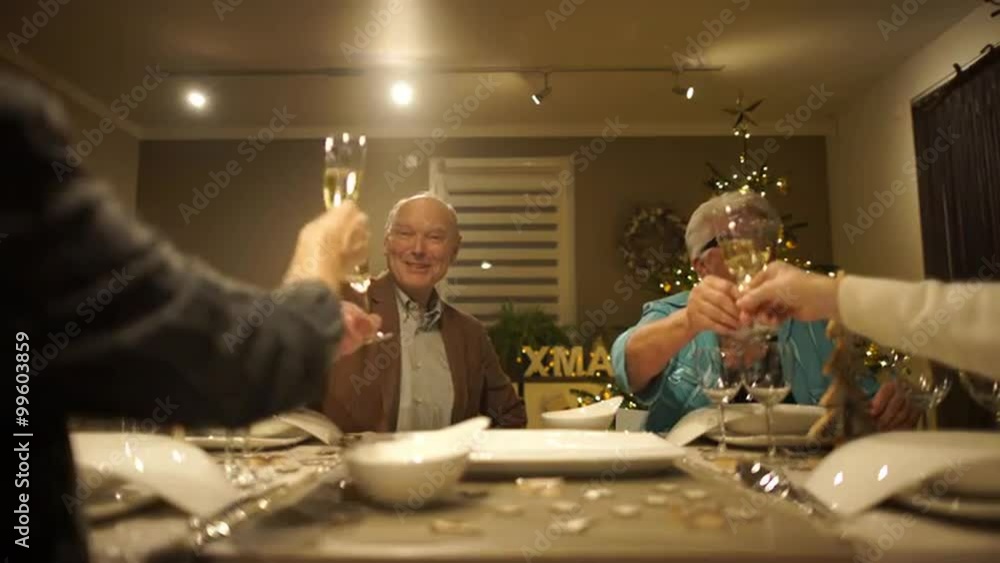 4k footage, four happy seniors sitting on dining table at home on christmas eve cheering with champagne, captured with atomos shogun
