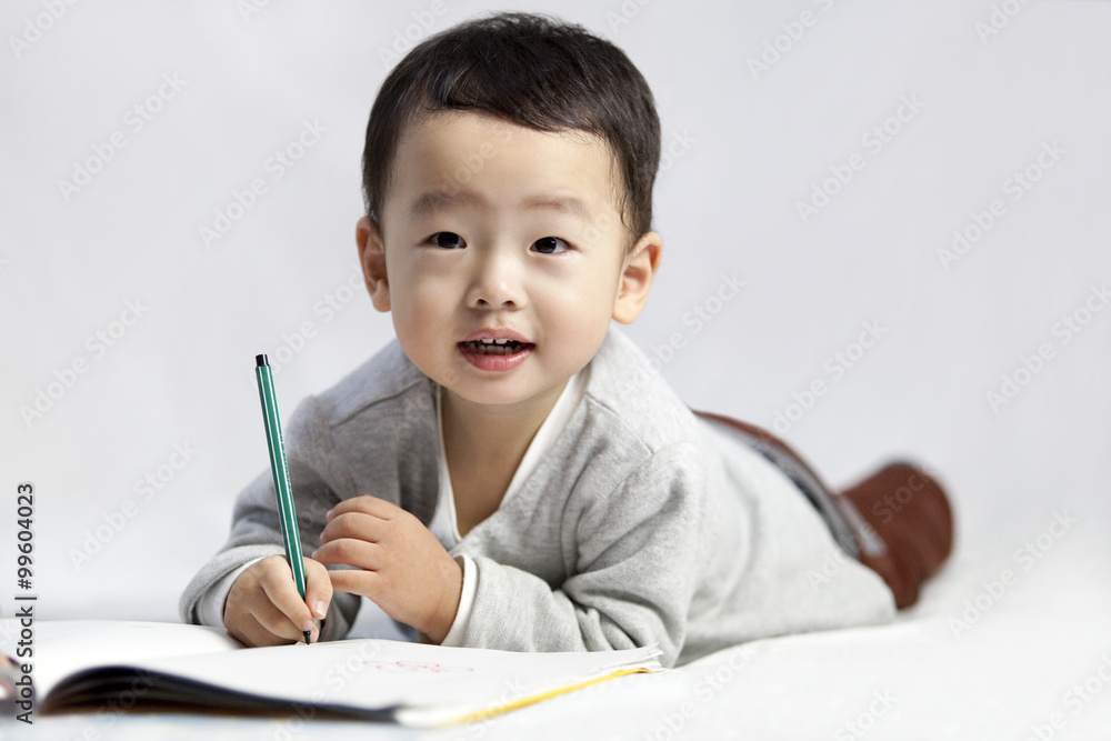 Cute little boy lying on front and writing Cute little boy lying on front and writing