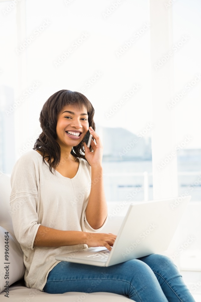 Smiling casual woman having a phone call while using laptop Smiling casual woman having a phone call while using laptop