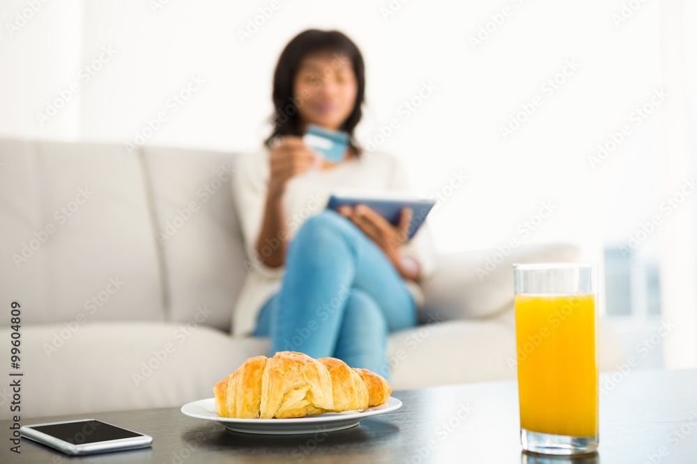 Casual woman using tablet while holding a card Casual woman using tablet while holding a card