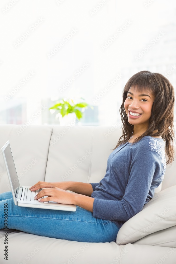 Casual smiling woman using laptop on the couch Casual smiling woman using laptop on the couch