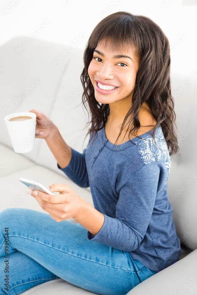 Casual smiling woman holding coffee and smartphone Casual smiling woman holding coffee and smartphone