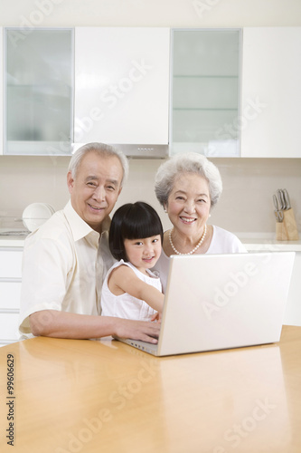 Little girl using a laptop with her grandparents