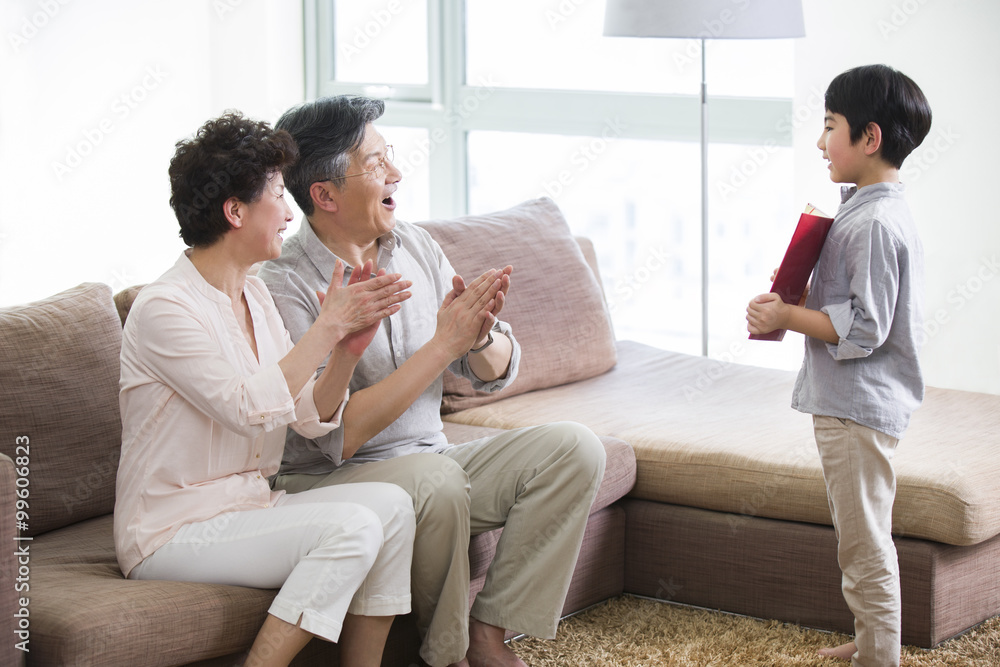 Cute boy showing certificate of merit to grandparents Cute boy showing certificate of merit to grandparents