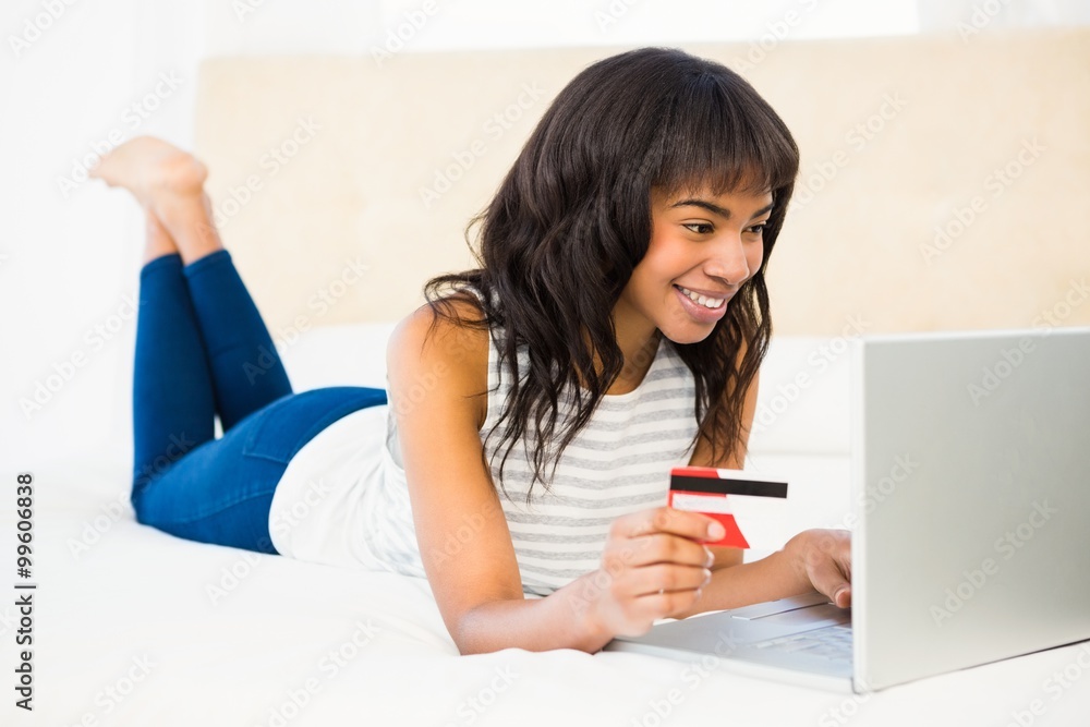 Casual smiling woman using laptop while holding a card Casual smiling woman using laptop while holding a card