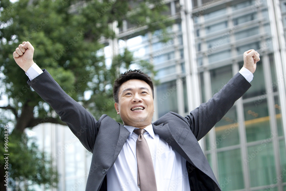 Mature businessman punching the air excitedly outdoors, Hong Kong