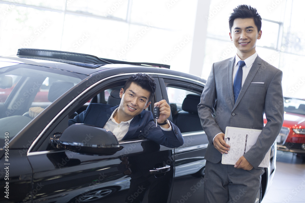 Young businessman buying car in showroom