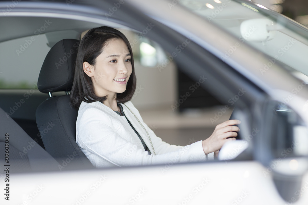 Young woman choosing car in showroom