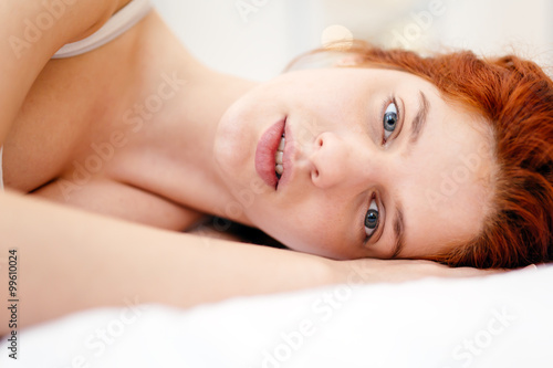 Beautiful red haired woman lying on bed