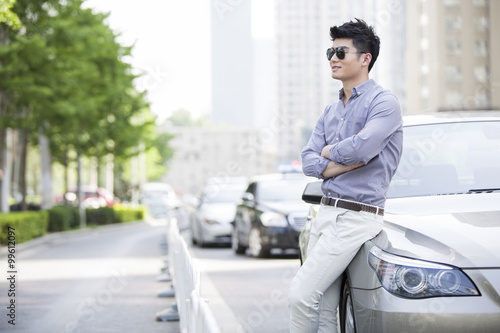 Young man leaning against his car © Blue Jean Images