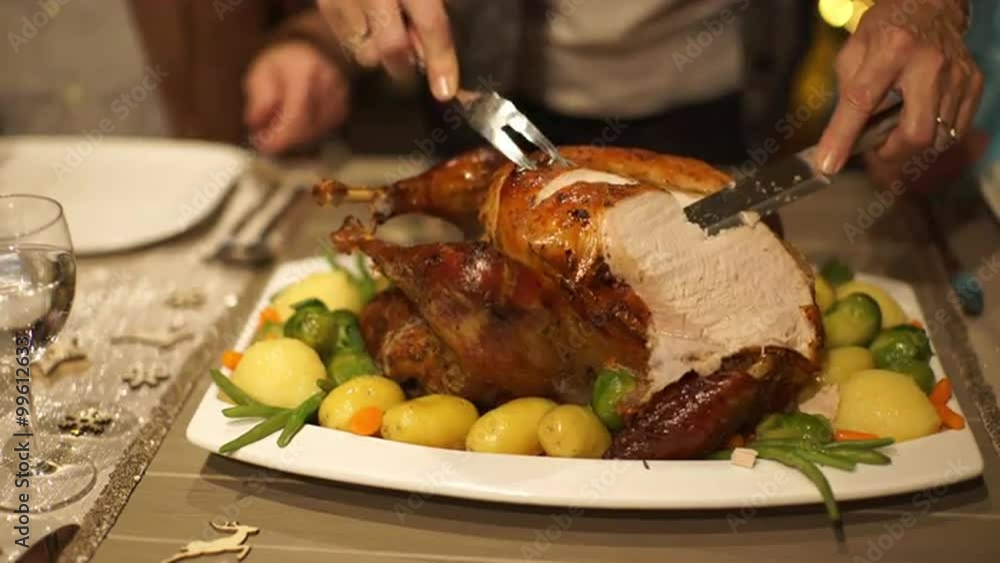 4k footage, detail woman cutting roasted christmas turkey on dining table and serving slices on plate, captured with atomos shogun
