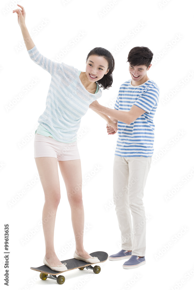 Young man teaching his girlfriend to skateboard Young man teaching his girlfriend to skateboard