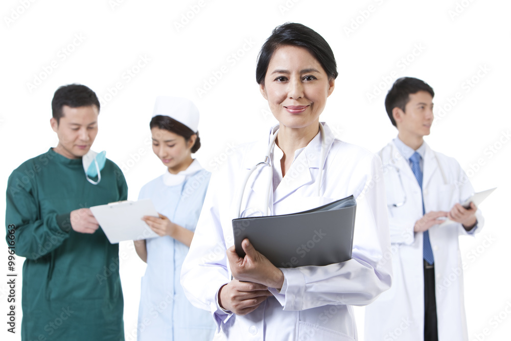 Smiling female doctor with her colleagues in background Smiling female doctor with her colleagues in background