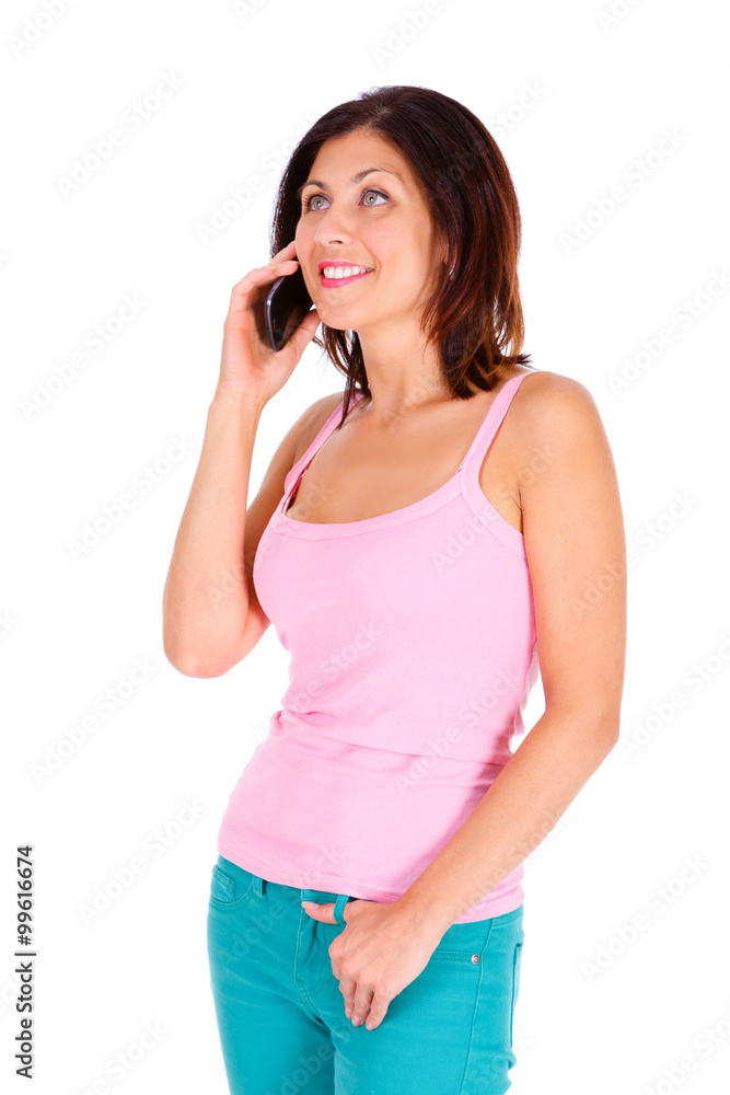 Portrait of smile slim brunette tanned woman with short hairstyle, dressed in t-shirt pink color and turquoise jeans, talking by cell mobile phone. Isolated on white background. Positive emotion Portrait of smile slim brunette tanned woman with short hairstyle, dressed in t-shirt pink color and turquoise jeans, talking by cell mobile phone. Isolated on white background. Positive emotion
