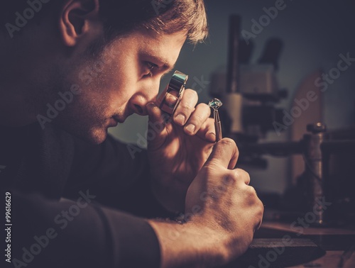 Jeweler looking at the ring through microscope in a workshop. photo