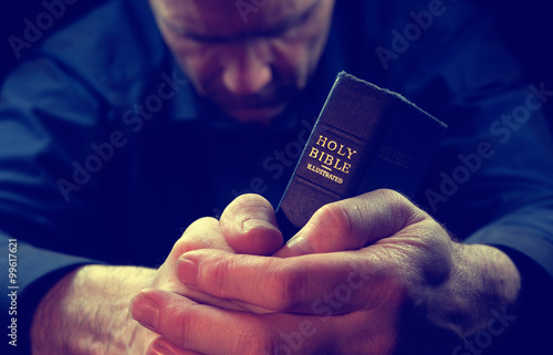 Obraz na płótnie A Man praying holding a Holy Bible. w salonie