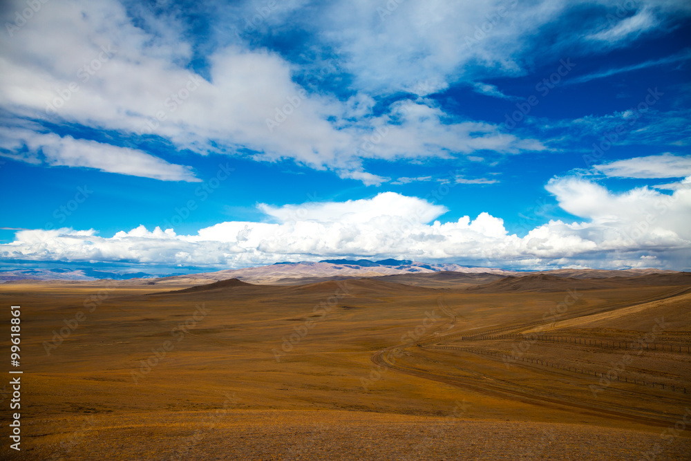 The road crosses the steppe, mountains, blue sky with clouds. Chuya Steppe  in the Siberian Altai Mountains, Russia