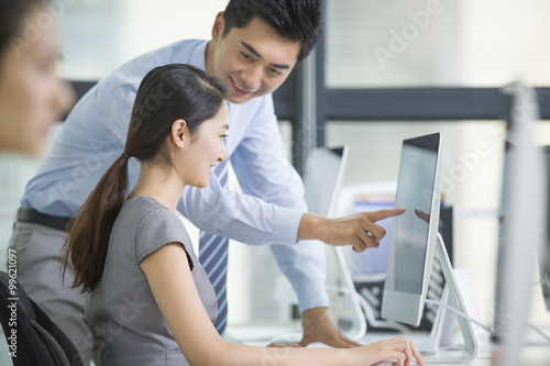 Young businesswoman and businessman talking in office