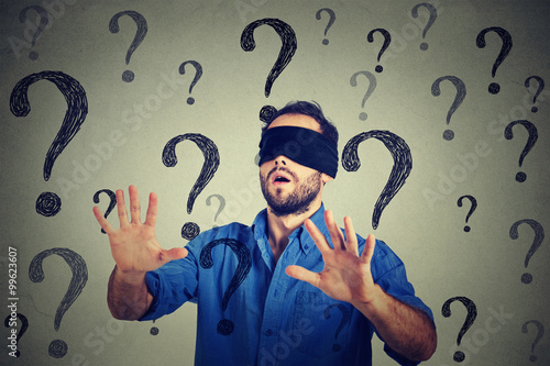 Quadro su tela Portrait business man blindfolded stretching his arms out walking through many q