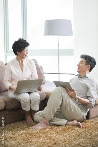Happy senior couple with laptop and digital tablet
