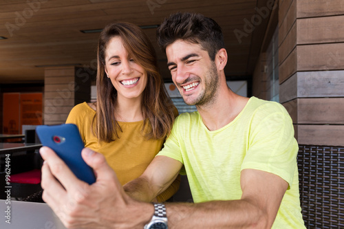 Fotografie Young caucasian couple look at the cellphone at the same time