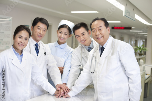 A medical staff huddled together with hands stacked together