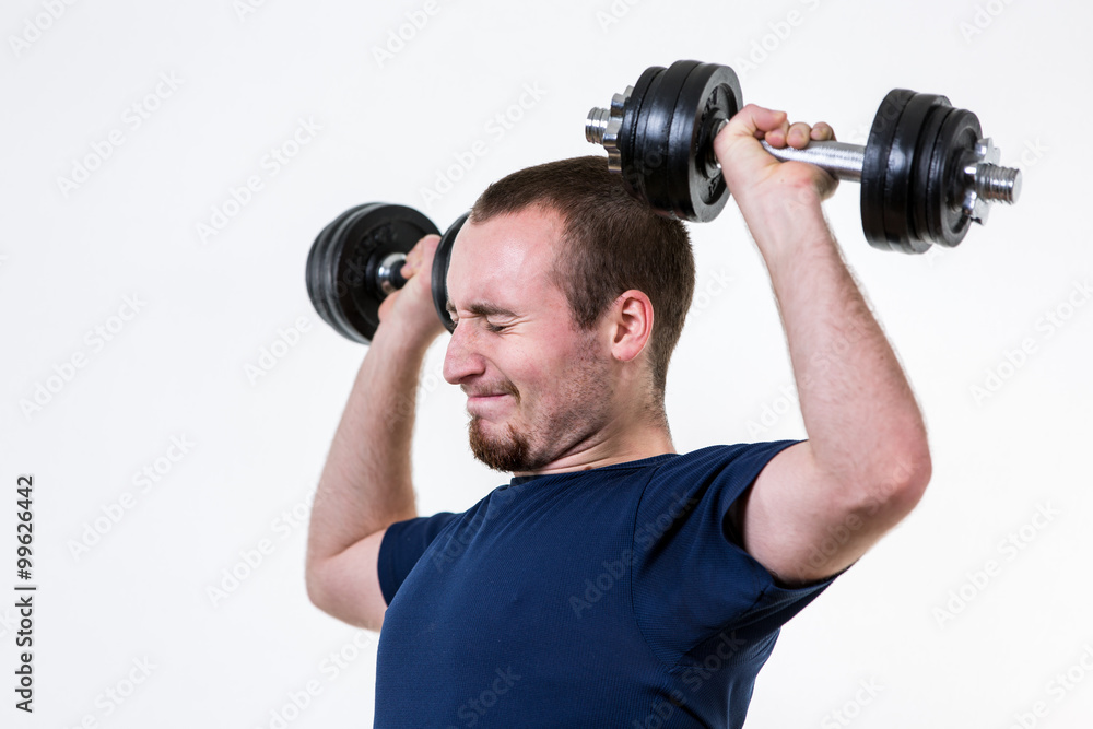 Close up of young man lifting weights over grey background Close up of young man lifting weights over grey background