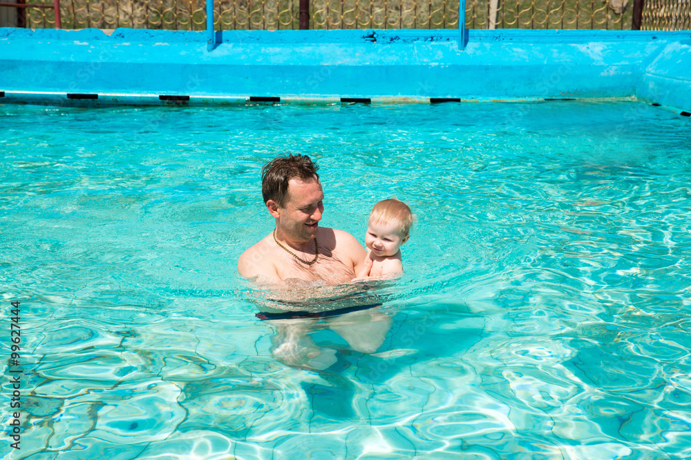 Active father teaching his child to swim in pool on tropical resort. Summer vacations and sport concept