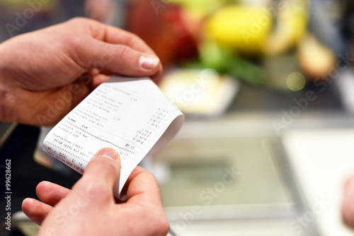 Foto Hände mit Kassenzettel an der Kasse im Supermarkt // hands with receipt at the c