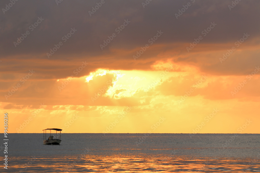 Ocean sunset with clouds in gold colors  with boat silhouette.
