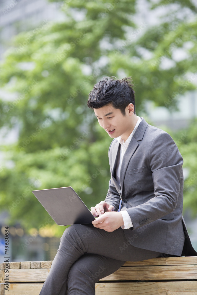 Young businessman working with laptop outdoors Young businessman working with laptop outdoors