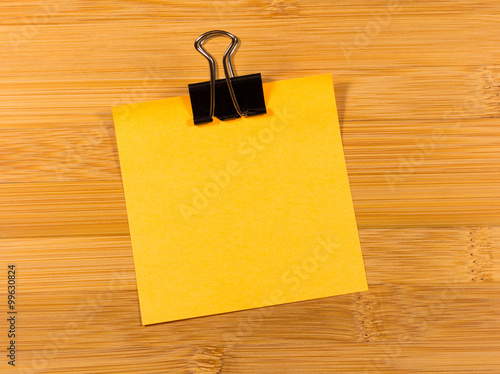 Sticky note on wooden background, empty space for text