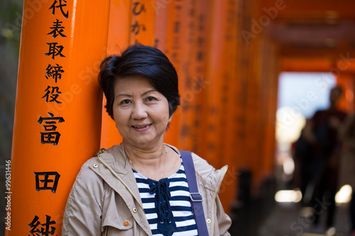 Travel Japan, middle-aged woman smiling to camera traveling at Fushimi Inari Shrine, Kyoto, Japan
