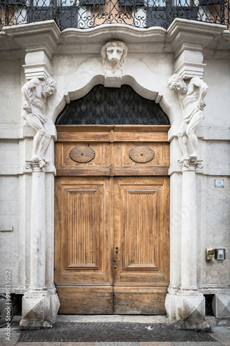 Old white stone entrance with statues and wooden portal.