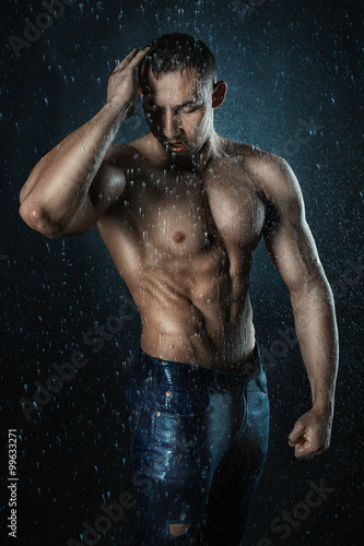 Man bodybuilder shakes off water from his hair. © Petro