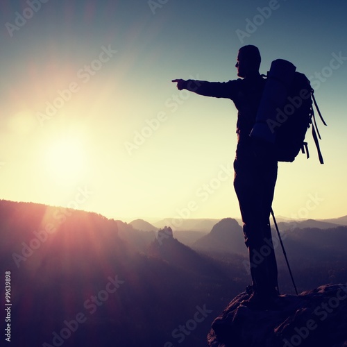 Obraz na płótnie Sharp silhouette of a tall man on the top of the mountain with sun in the frame