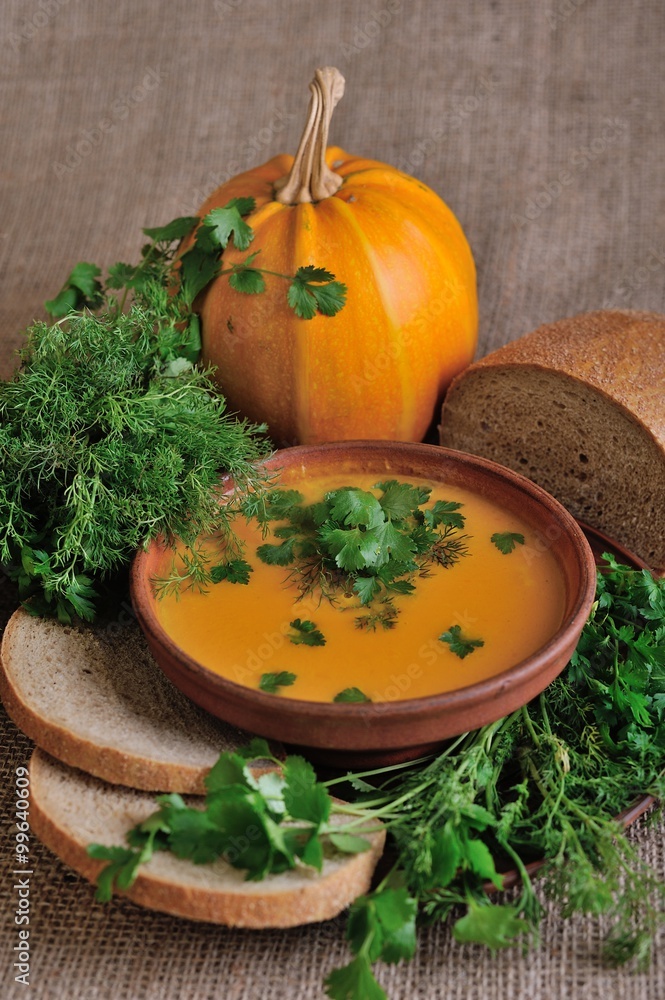 Pumpkin Soup; a bowl of pumpkin soup with bundle of greens and slices of bread Pumpkin Soup; a bowl of pumpkin soup with bundle of greens and slices of bread