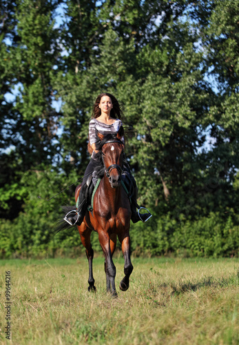 Pretty girl riding in the forest road in summer evening