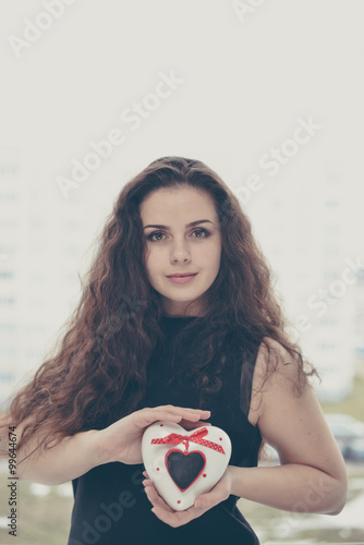 Pretty woman in love holding heart-shaped box photo