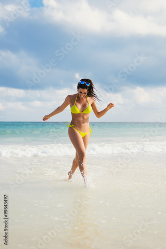 Joyful woman having fun at seashore on summer beach vacation. Bikini girl running and laughing.
