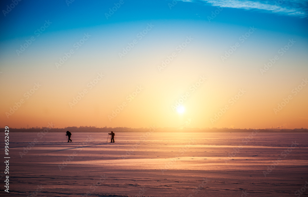 Beautiful winter sunset landscape with cross-country skiers Beautiful winter sunset landscape with cross-country skiers