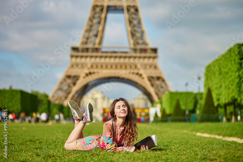 Photography Beautiful young woman in Paris lying on the grass near the Eiffel tower