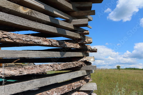 Ends of the rough pine boards in the outdoor stack against a blue sky photo