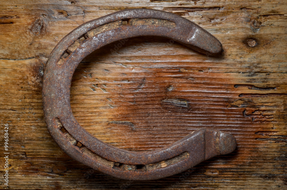 rusty horse shoe on wood table shaped like letter c rusty horse shoe on wood table shaped like letter c